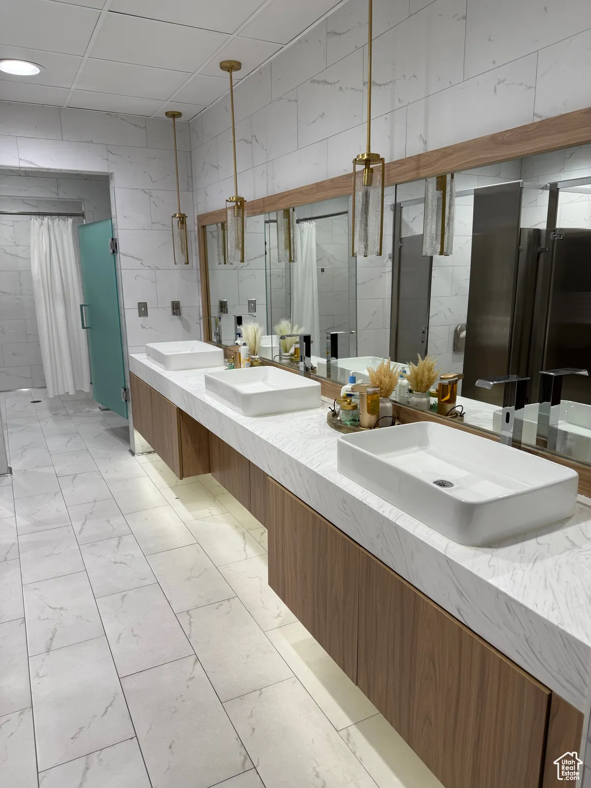 Full bathroom with a shower stall, double vanity, marble finish floor, and a sink