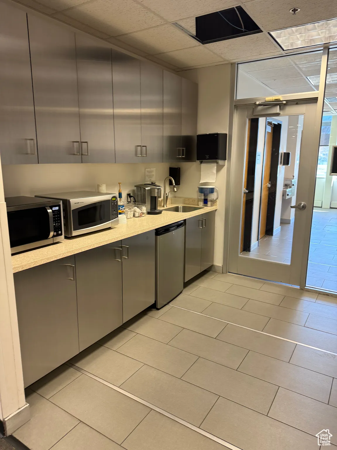 Kitchen with light countertops, gray cabinets, a sink, and stainless steel appliances