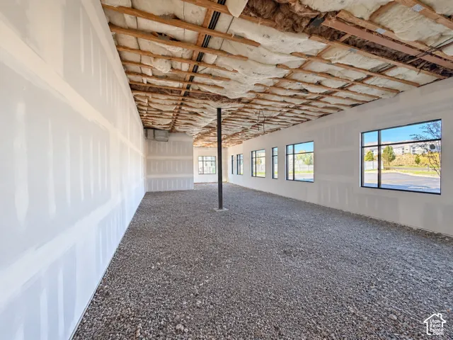 Expansive interior space featuring drywall-finished perimeter walls, multiple large-pane windows, and a central structural support column