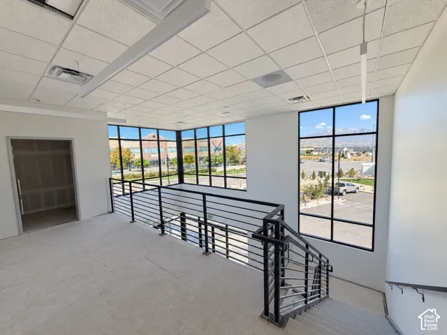 Open-concept space featuring a dropped ceiling, expansive floor-to-ceiling windows, metal railing staircase, and mountain scenery
