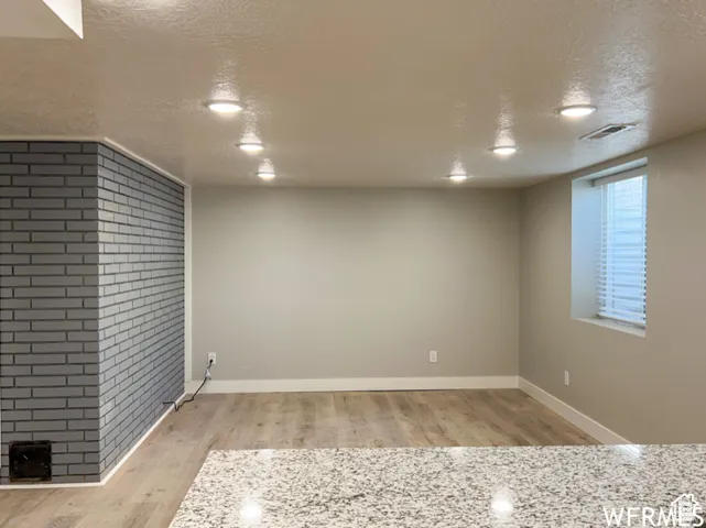 Basement with baseboards, visible vents, wood finished floors, and a textured ceiling