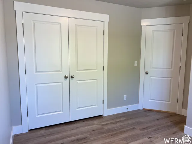 Unfurnished bedroom featuring a closet, baseboards, and wood finished floors