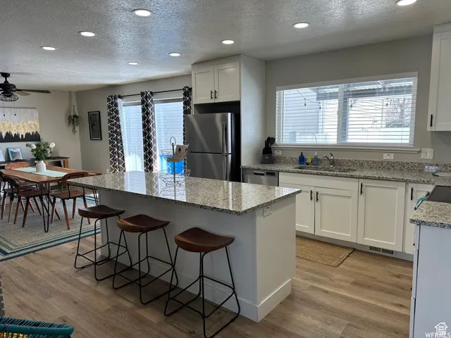 Kitchen featuring light wood finished floors, a sink, a center island, and appliances with stainless steel finishes