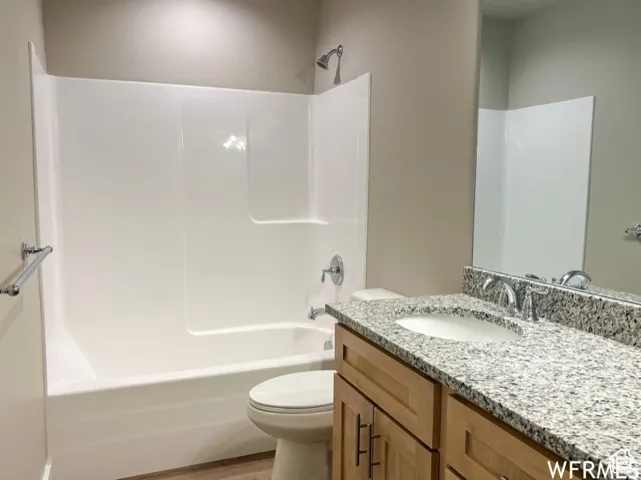Bathroom with shower / washtub combination, wood finished floors, toilet, and vanity