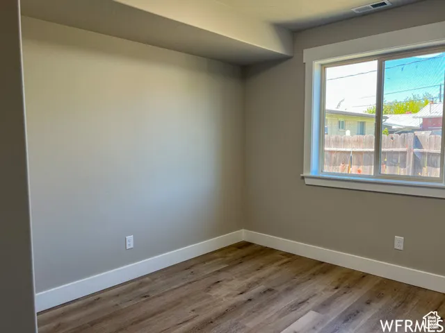 Unfurnished room with baseboards, visible vents, and wood finished floors