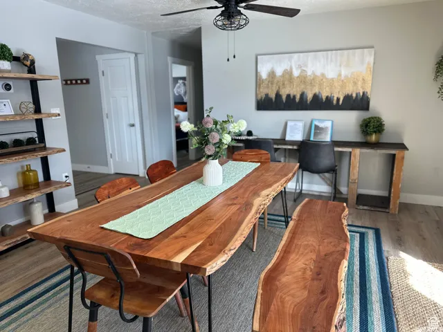 Dining space featuring a textured ceiling, baseboards, ceiling fan, and wood finished floors