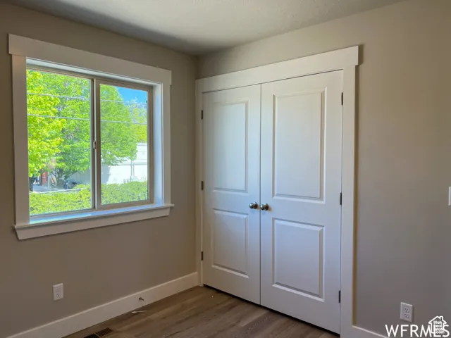 Unfurnished bedroom featuring a closet, baseboards, and wood finished floors