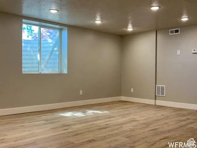 Interior space featuring baseboards, visible vents, wood finished floors, and a textured ceiling