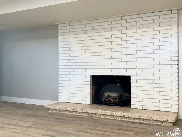 Room details with baseboards, wood finished floors, and a brick fireplace
