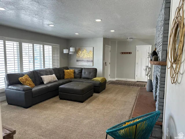 Living area with baseboards, a textured ceiling, and recessed lighting