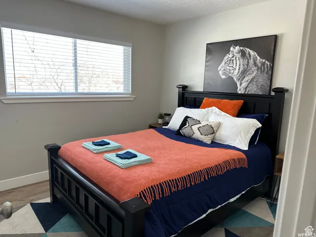 Bedroom with baseboards, multiple windows, a textured ceiling, and wood finished floors