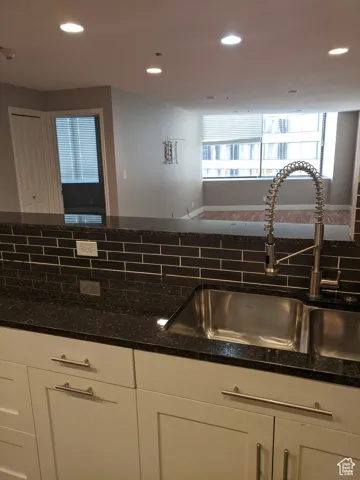 Kitchen with white cabinetry, decorative backsplash, a sink, and recessed lighting.