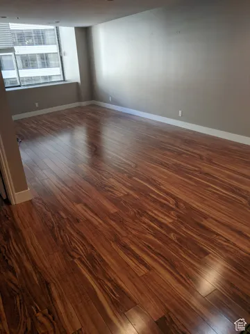 Living room featuring dark wood-style flooring and baseboards.  The condo is fully furnished.