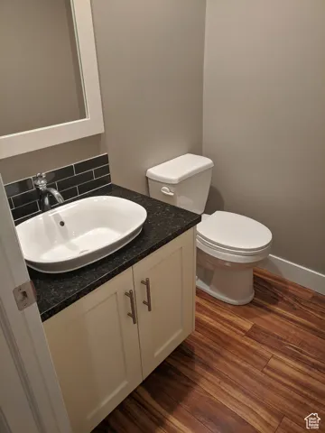 Bathroom featuring toilet, vanity, decorative backsplash, and wood finished floors