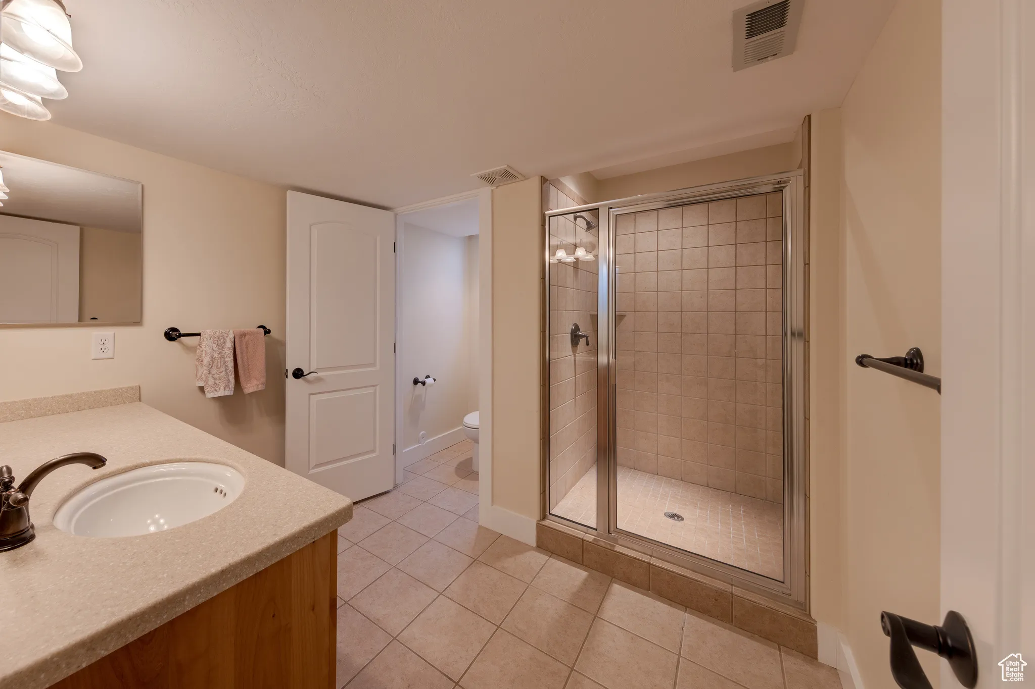 Bathroom with a stall shower, tile patterned floors, visible vents, and toilet