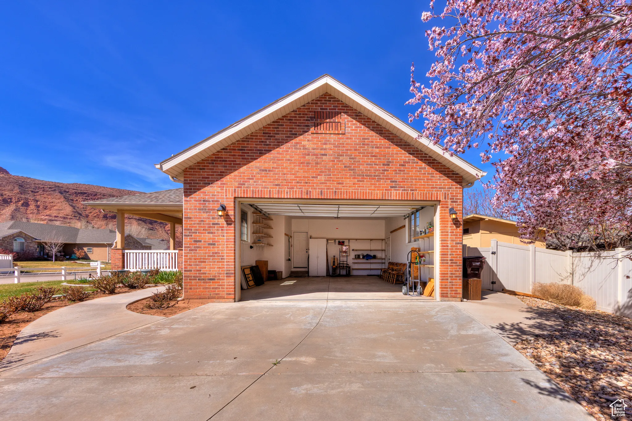 Exterior space featuring concrete driveway, fence, a gate, brick siding, and a garage