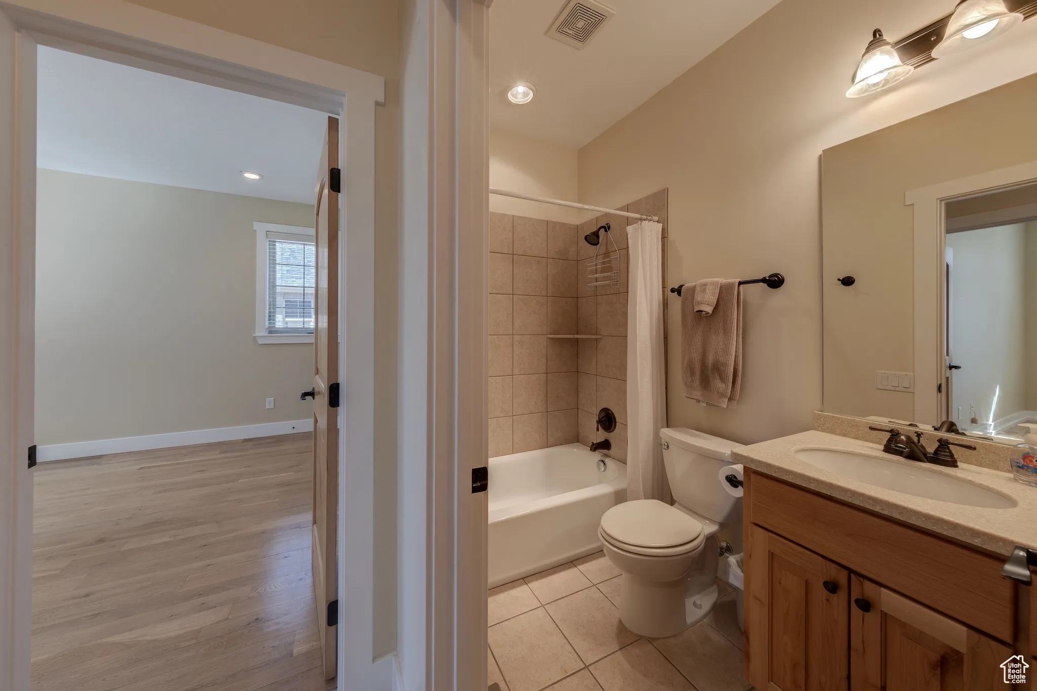 Bathroom with visible vents, toilet, tile patterned floors, vanity, and shower / bath combo with shower curtain