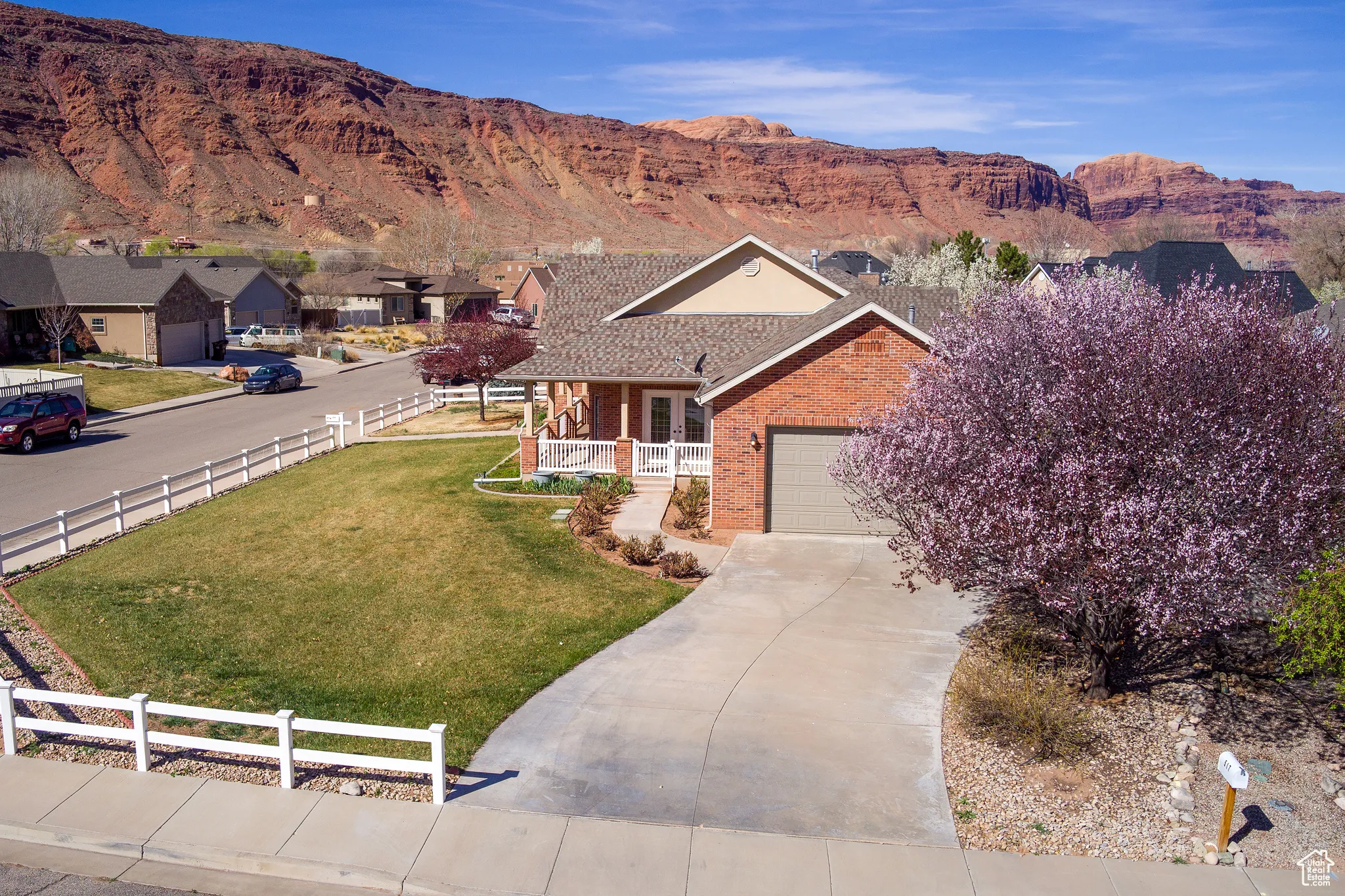 Single story home featuring driveway, a front yard, fence, brick siding, and a mountain view