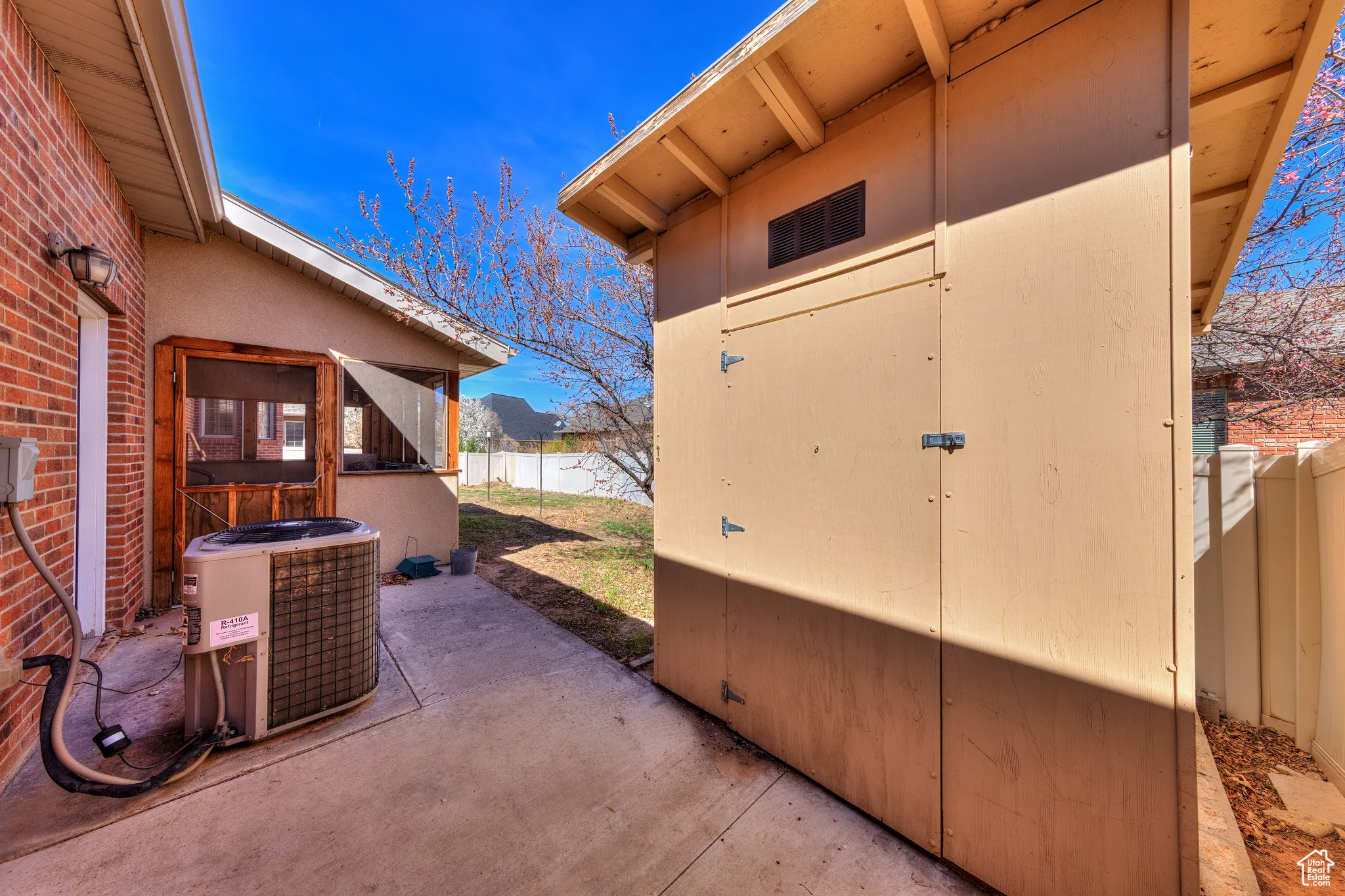 View of patio featuring an outbuilding, cooling unit, a shed, and a fenced backyard