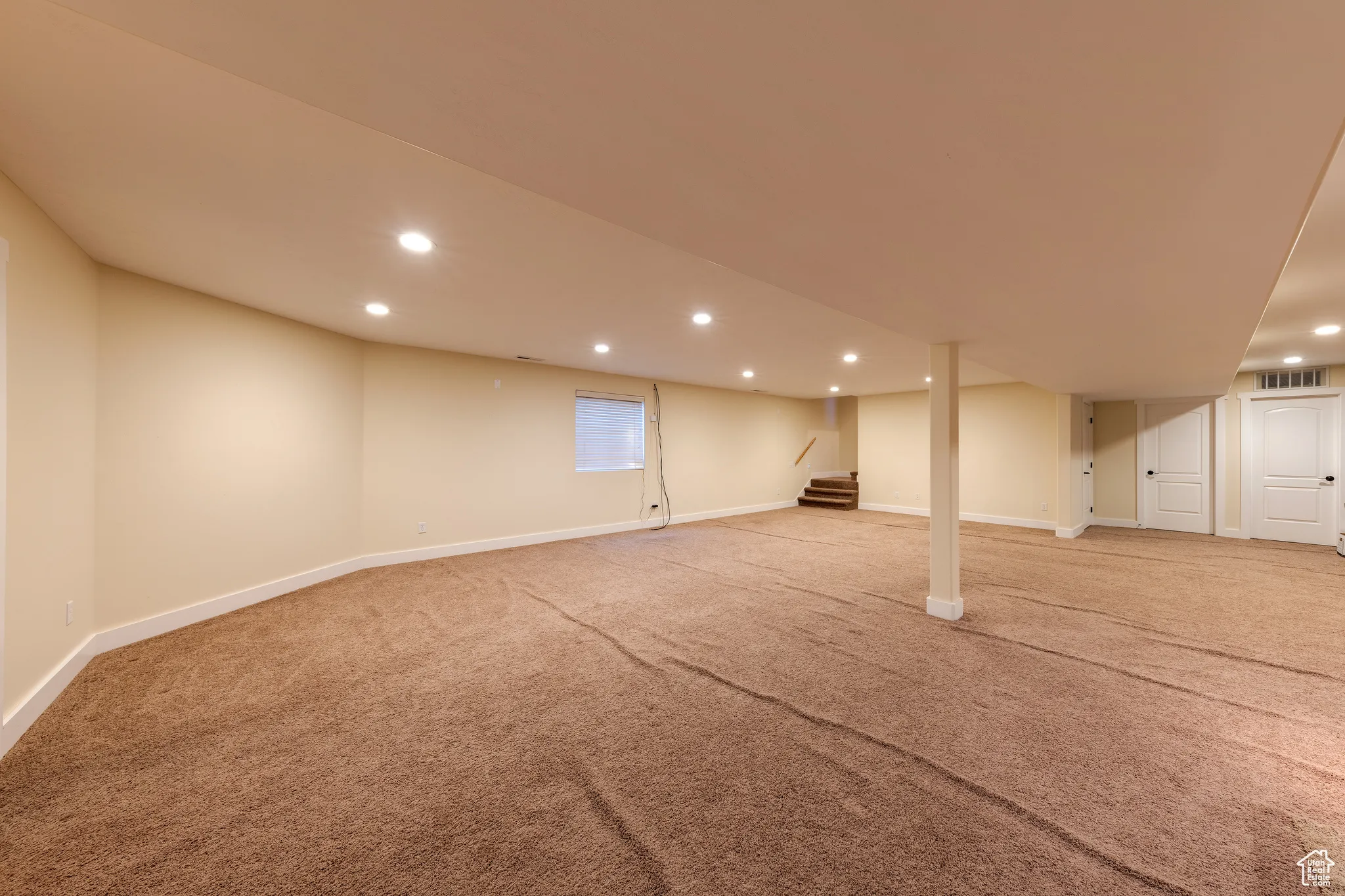 Finished basement featuring light carpet, baseboards, stairway, and recessed lighting