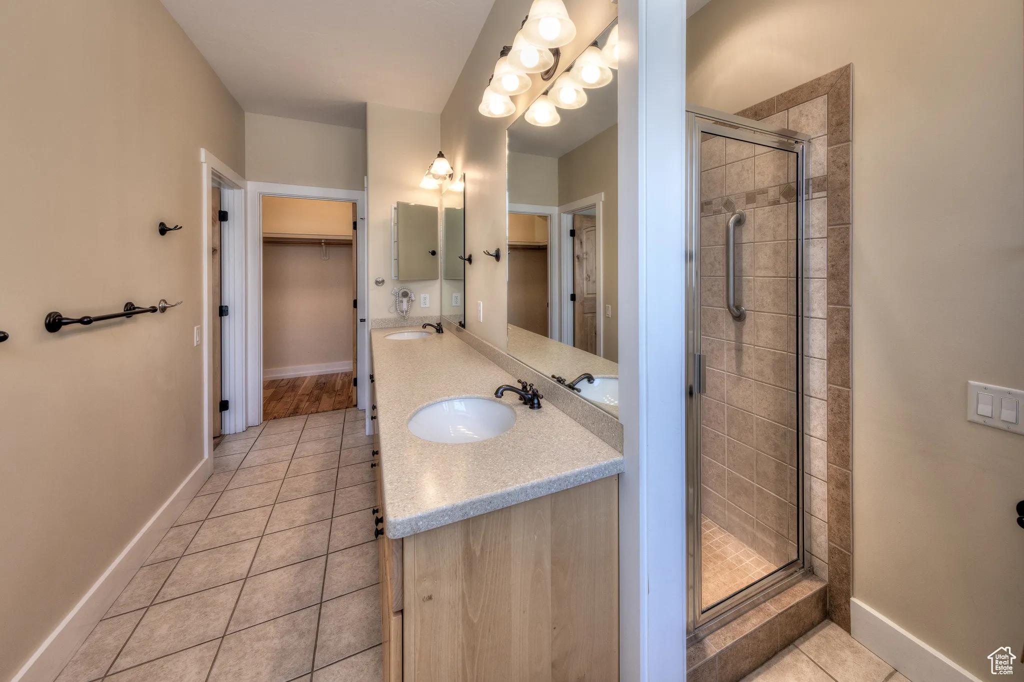 Bathroom featuring a walk in closet, a sink, tile patterned flooring, and a shower stall