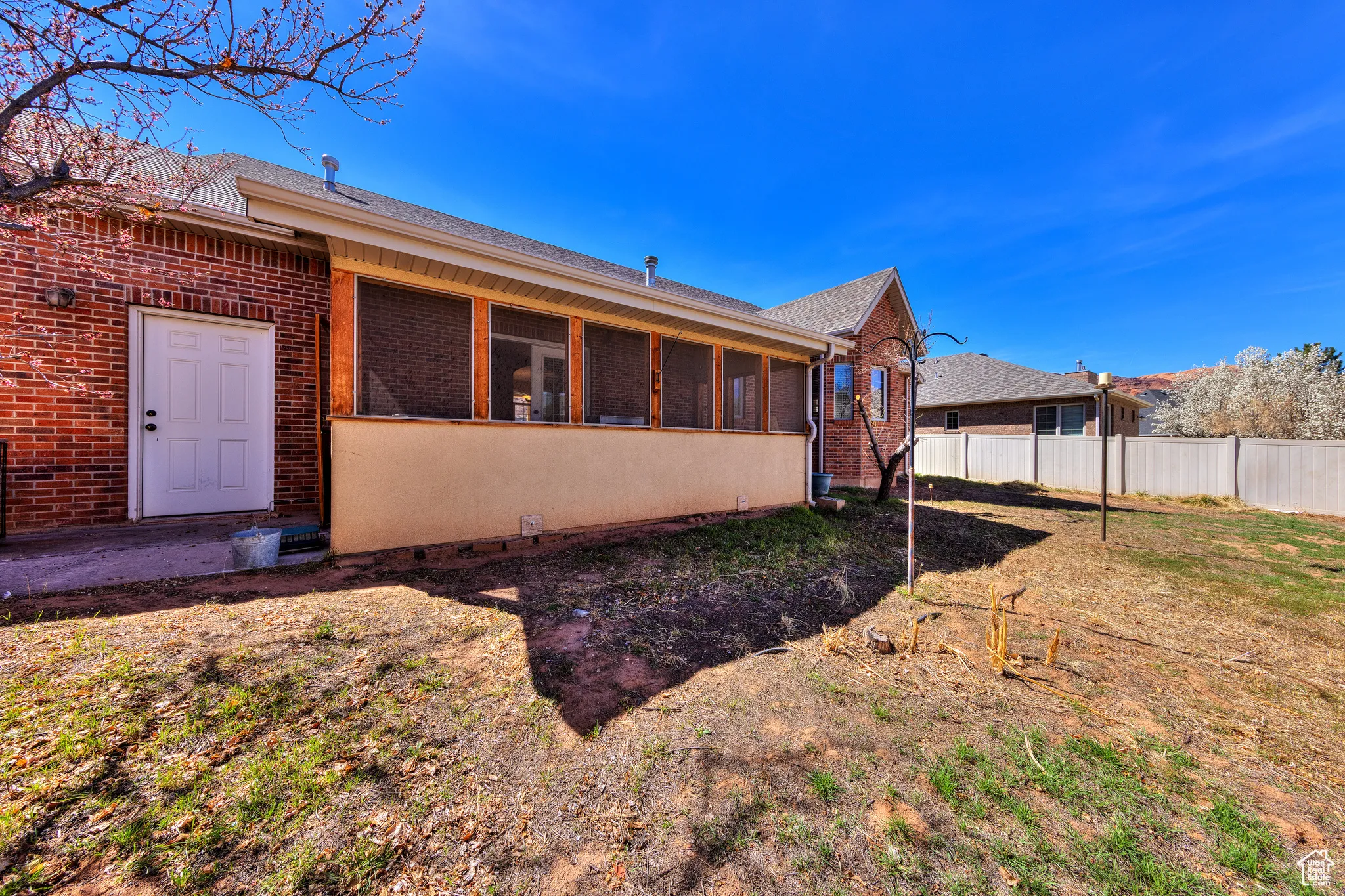Exterior space featuring brick siding, a sunroom, and fence