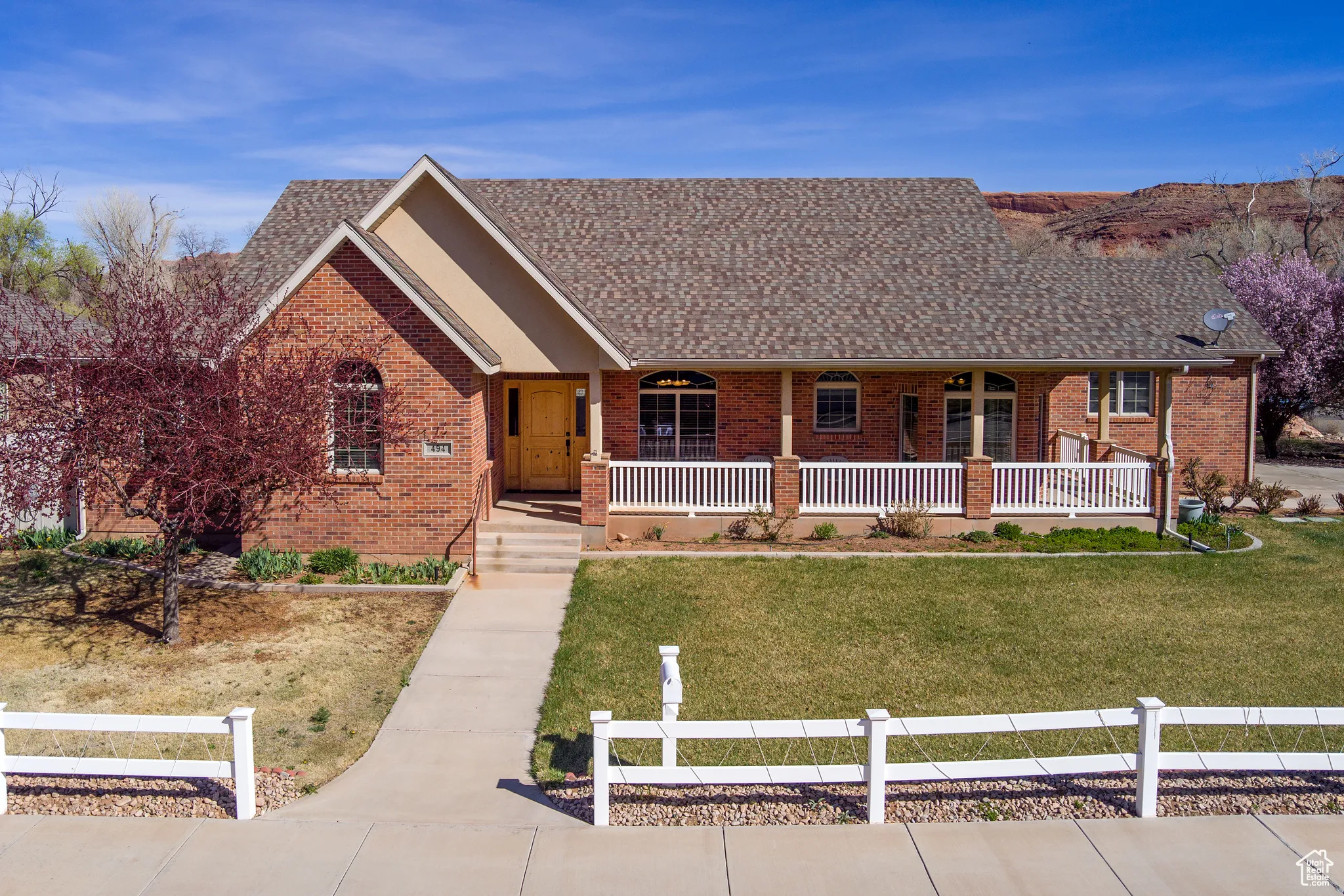 Single story home featuring covered porch, a front lawn, brick siding, and roof with shingles