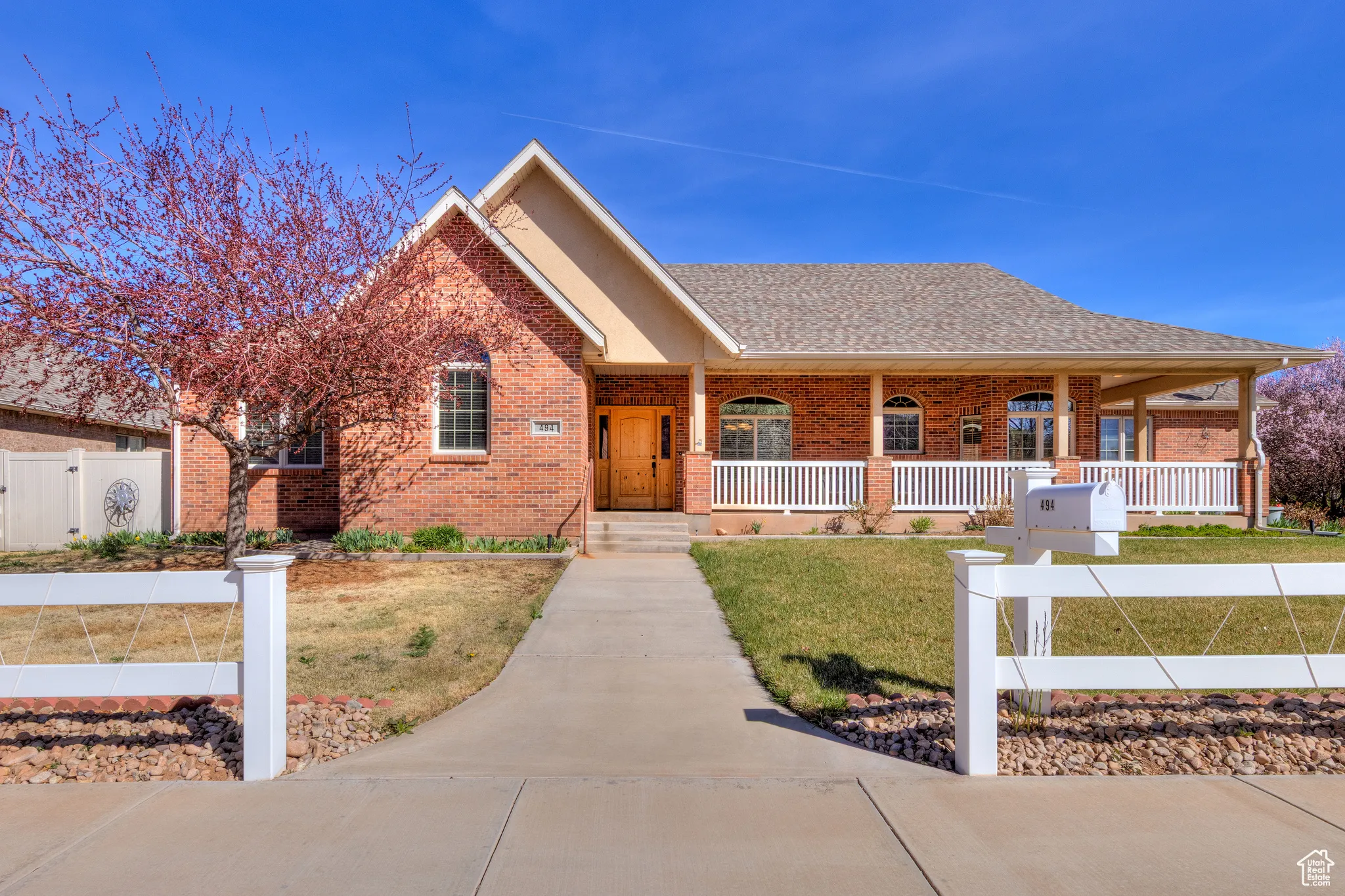 Single story home with a gate, fence, a front yard, brick siding, and covered porch