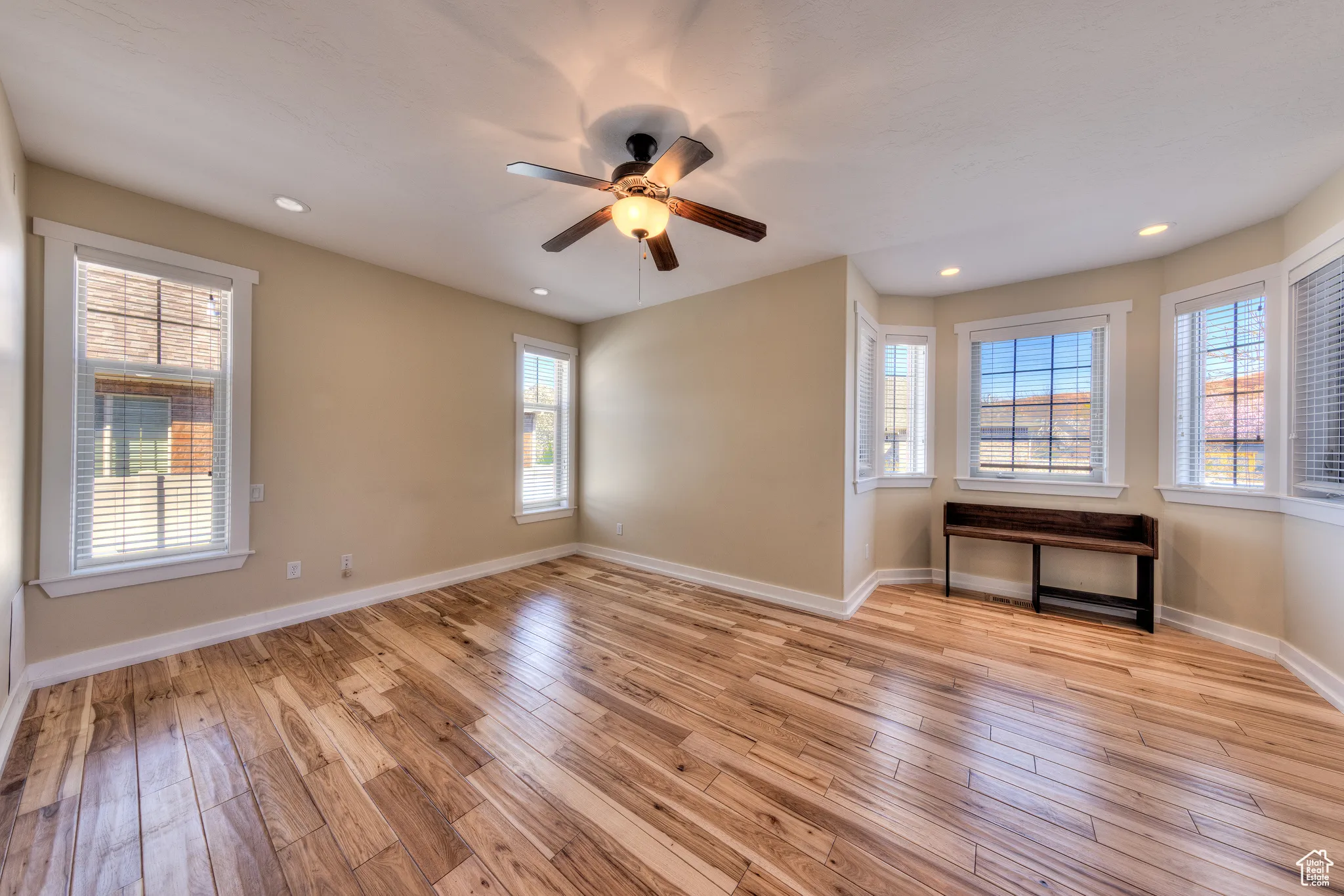 Unfurnished room featuring baseboards, light wood-style floors, ceiling fan, and recessed lighting