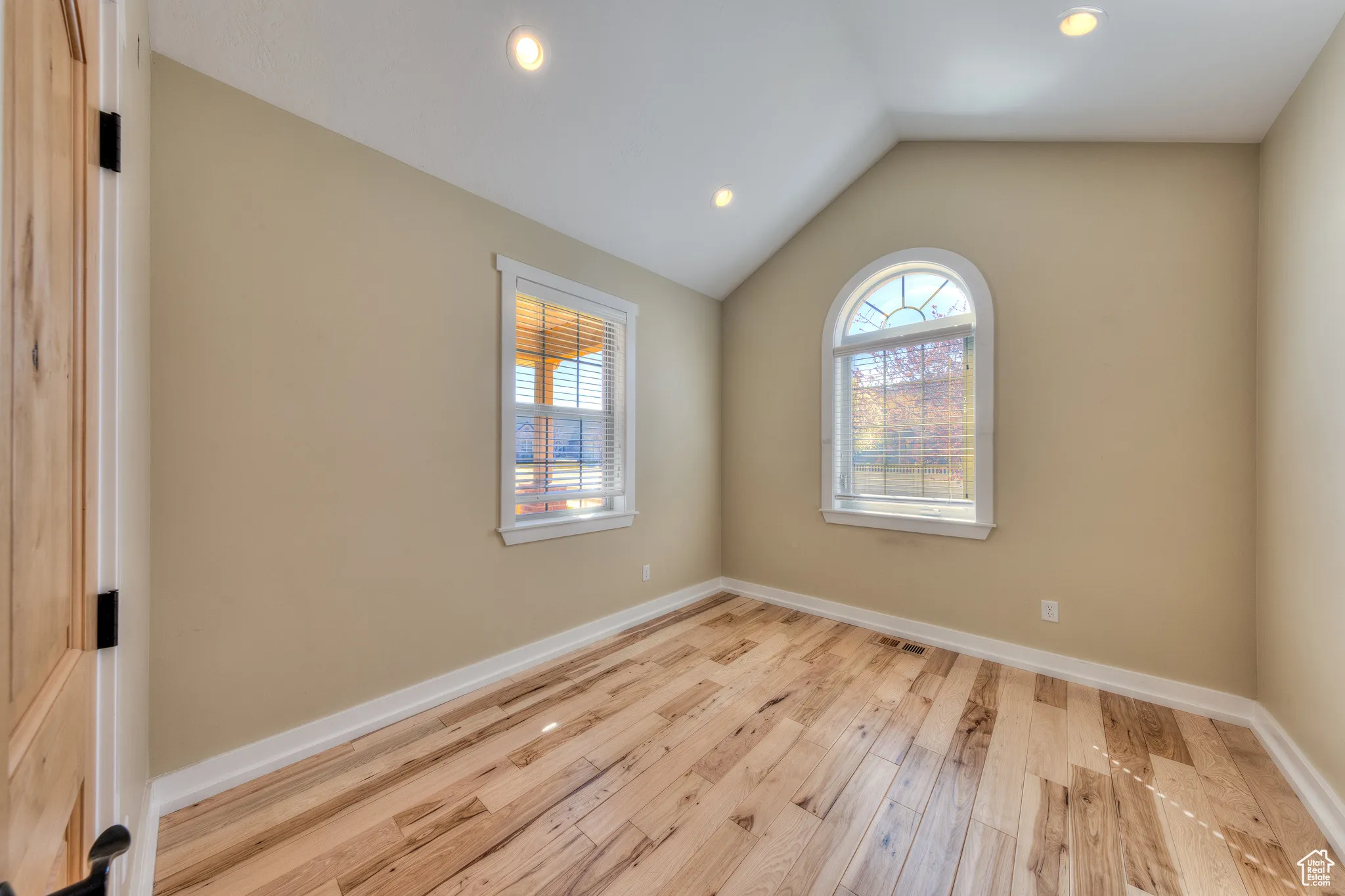 Spare room with plenty of natural light, baseboards, lofted ceiling, and wood finished floors