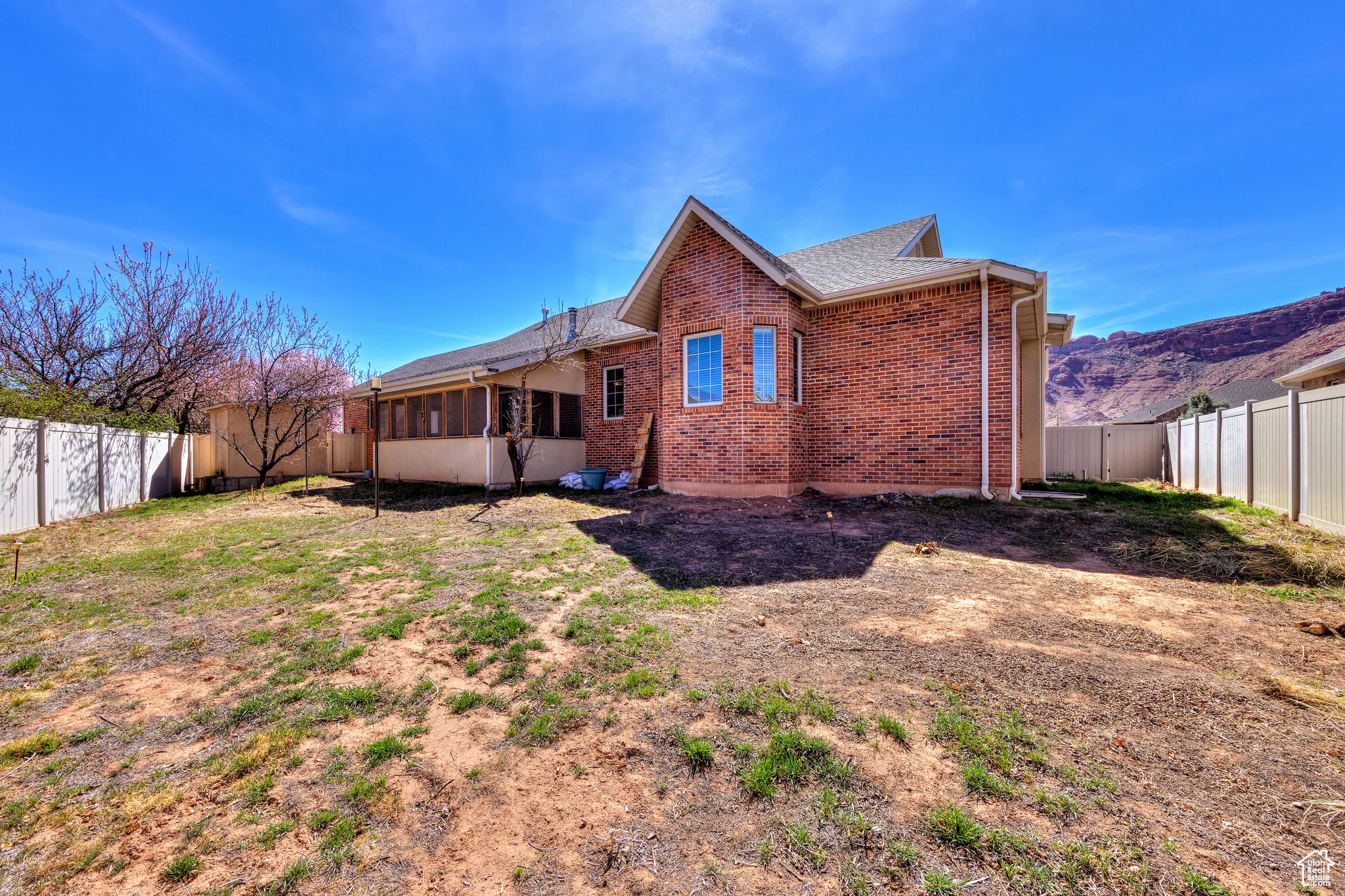 Rear view of property with a fenced backyard, brick siding, and roof with shingles
