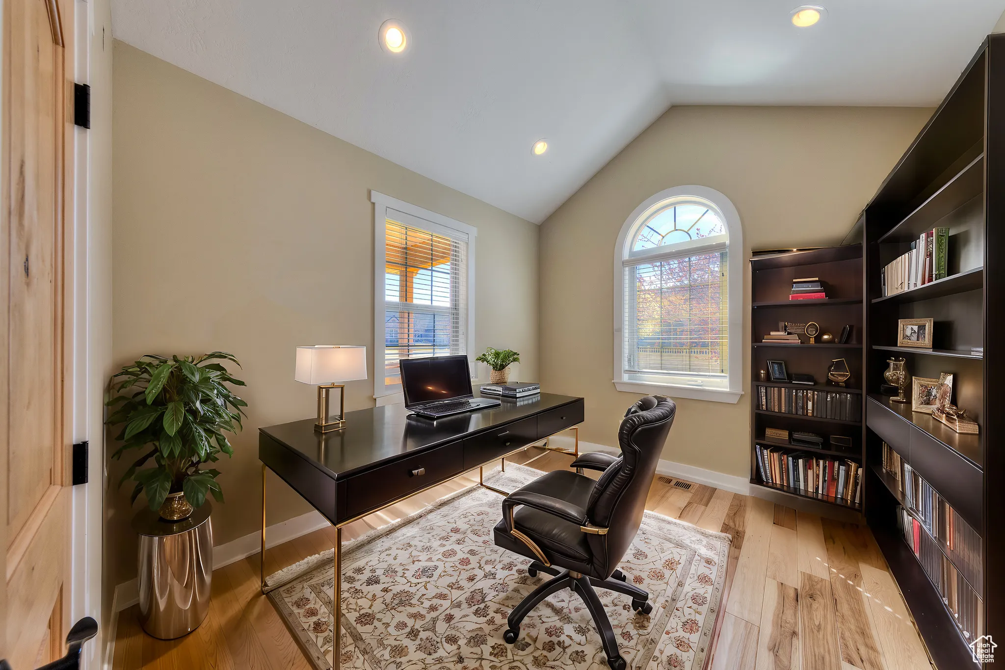 Office space with baseboards, a wealth of natural light, wood finished floors, and vaulted ceiling