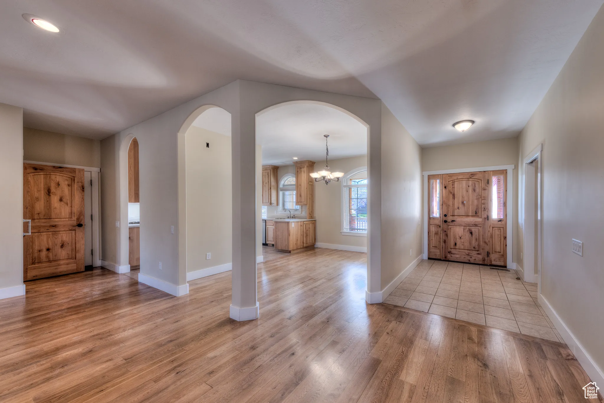 Entryway featuring an inviting chandelier, light wood-style flooring, arched walkways, and baseboards