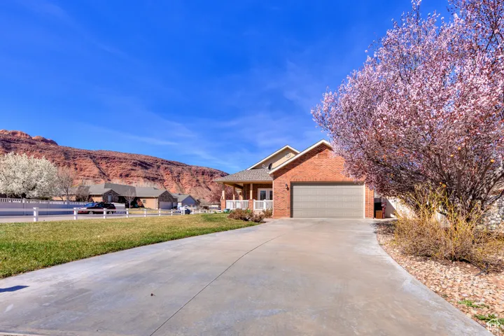 View of front of house featuring an attached garage, a front yard, brick siding, driveway, and a mountain view