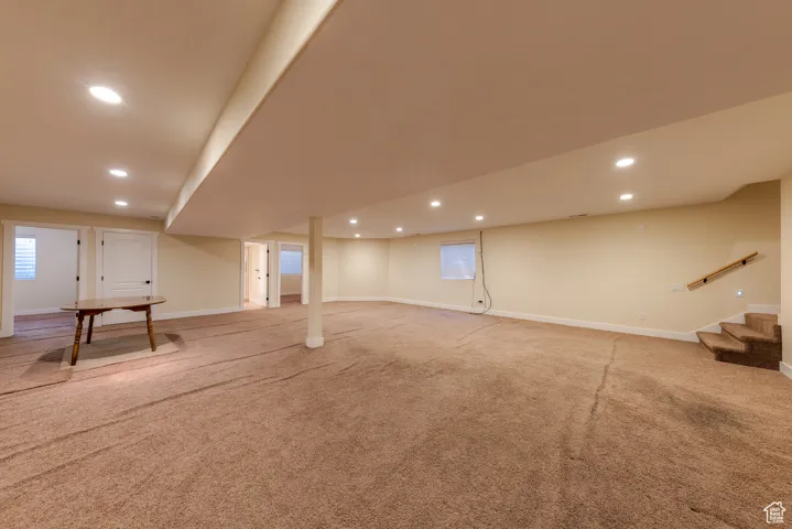 Below grade area featuring baseboards, stairway, light colored carpet, and recessed lighting