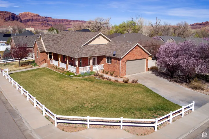 Ranch-style house with an attached garage, driveway, a front lawn, brick siding, and fence private yard
