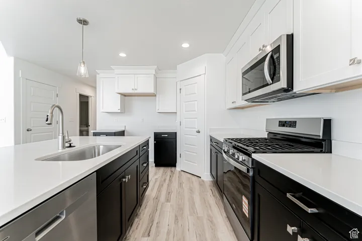Kitchen with appliances with stainless steel finishes, dark cabinets, white cabinetry, recessed lighting, and light countertops