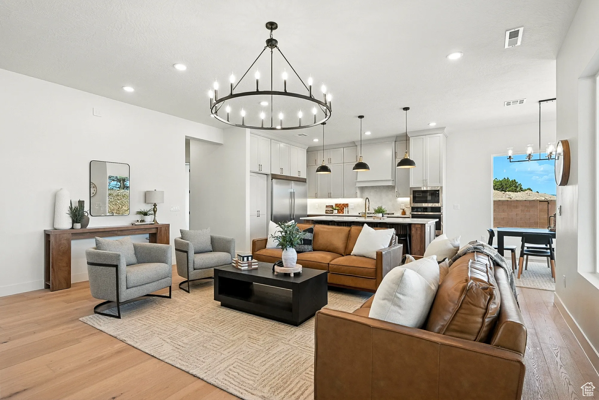 Living area with a chandelier, light wood-style flooring, and recessed lighting