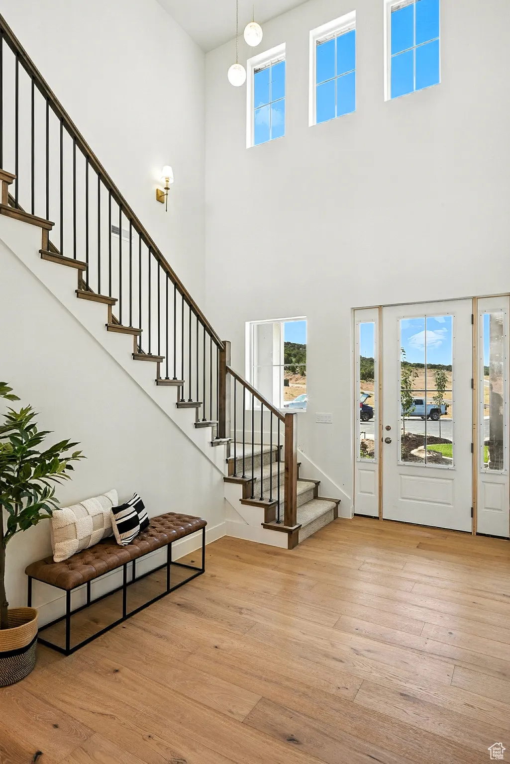 Entryway featuring stairs, light wood finished floors, and a towering ceiling