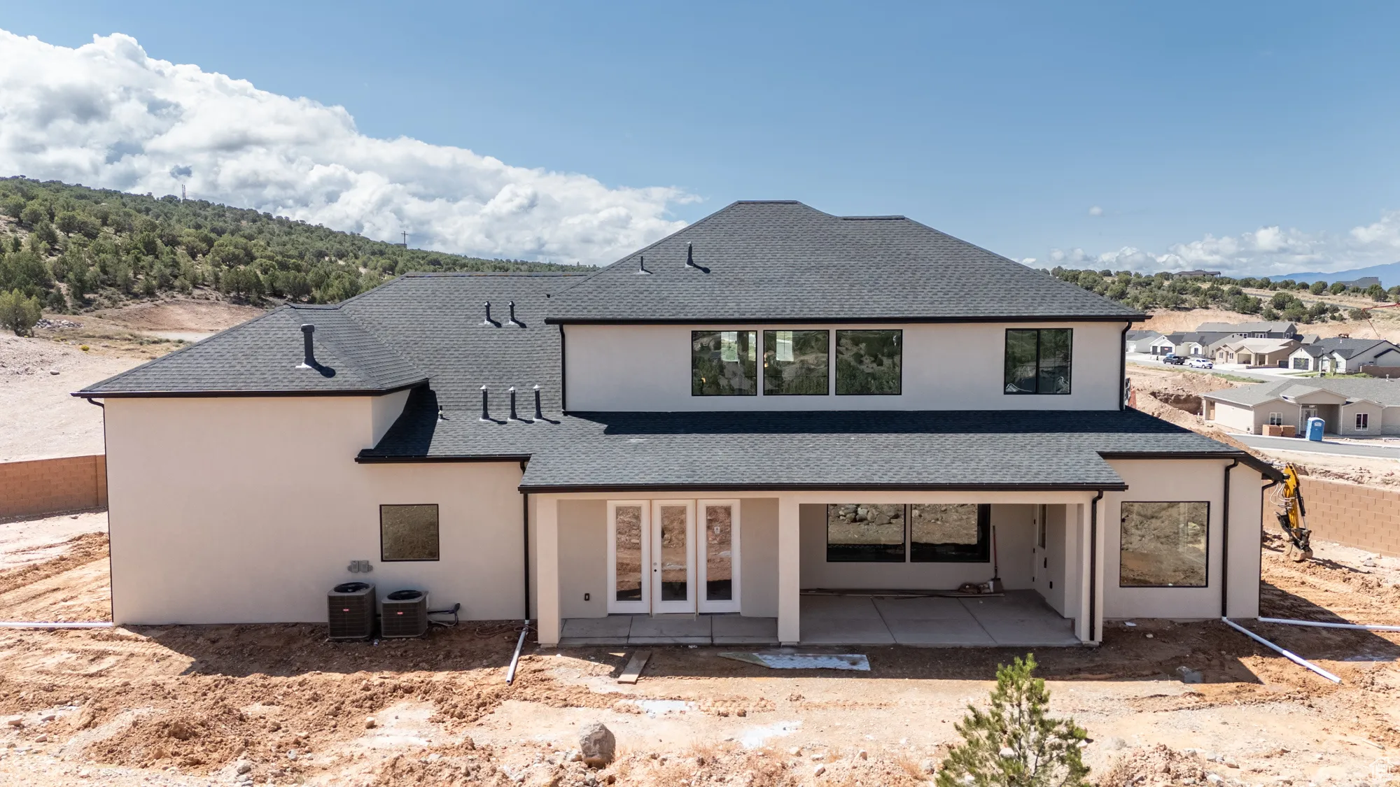 Rear view of house featuring a patio area, a shingled roof, stucco siding, and french doors