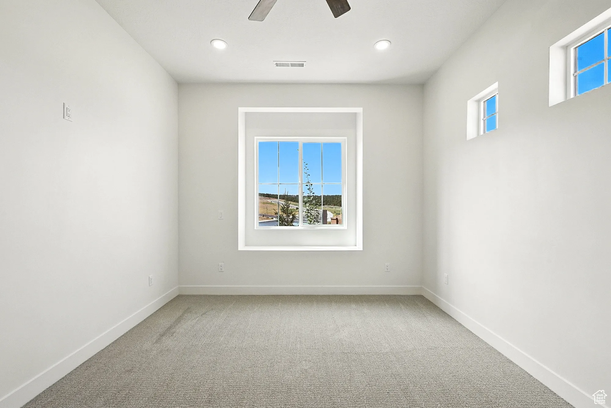 Spare room with plenty of natural light, light colored carpet, ceiling fan, and recessed lighting