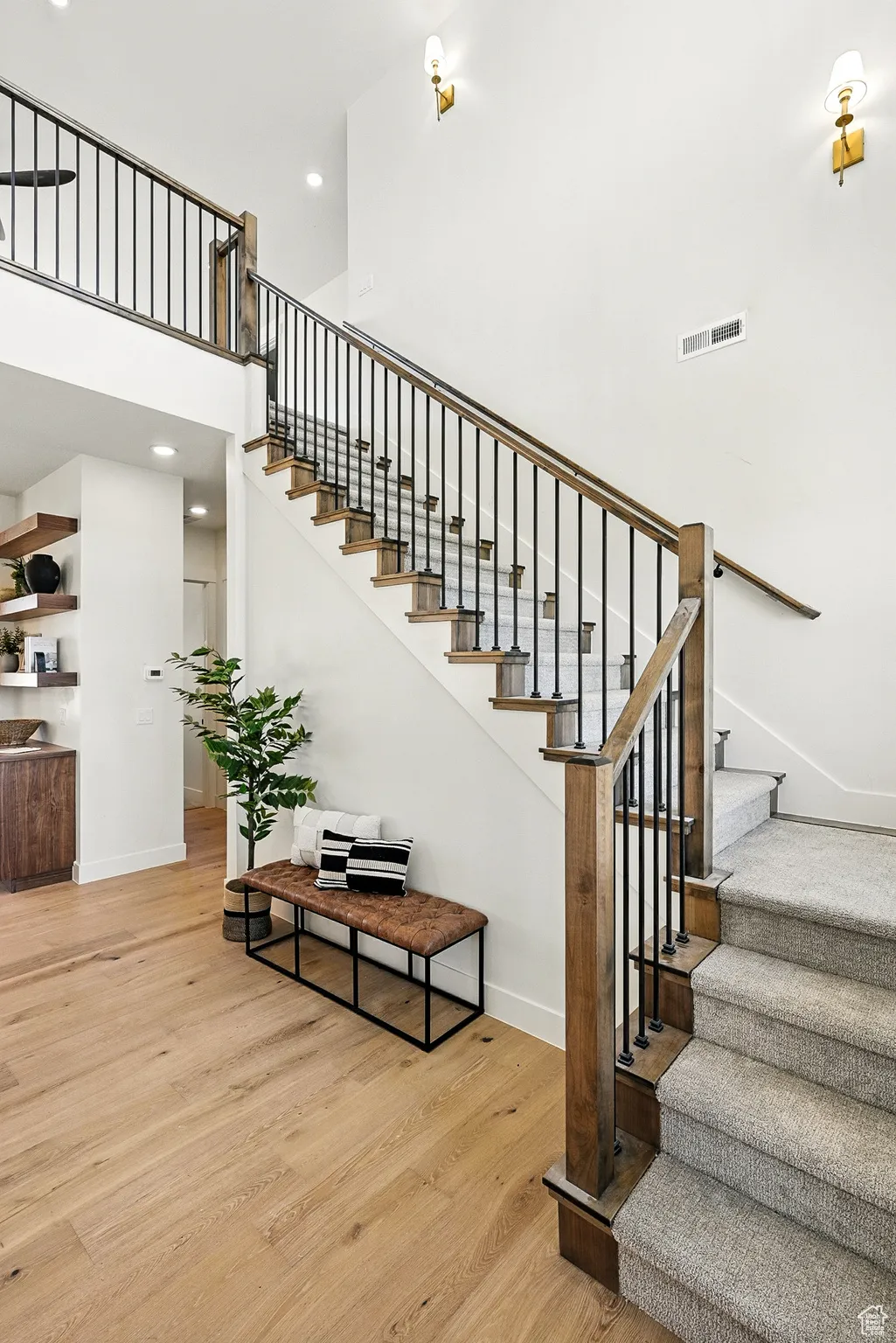 Staircase with a towering ceiling, wood finished floors, and recessed lighting