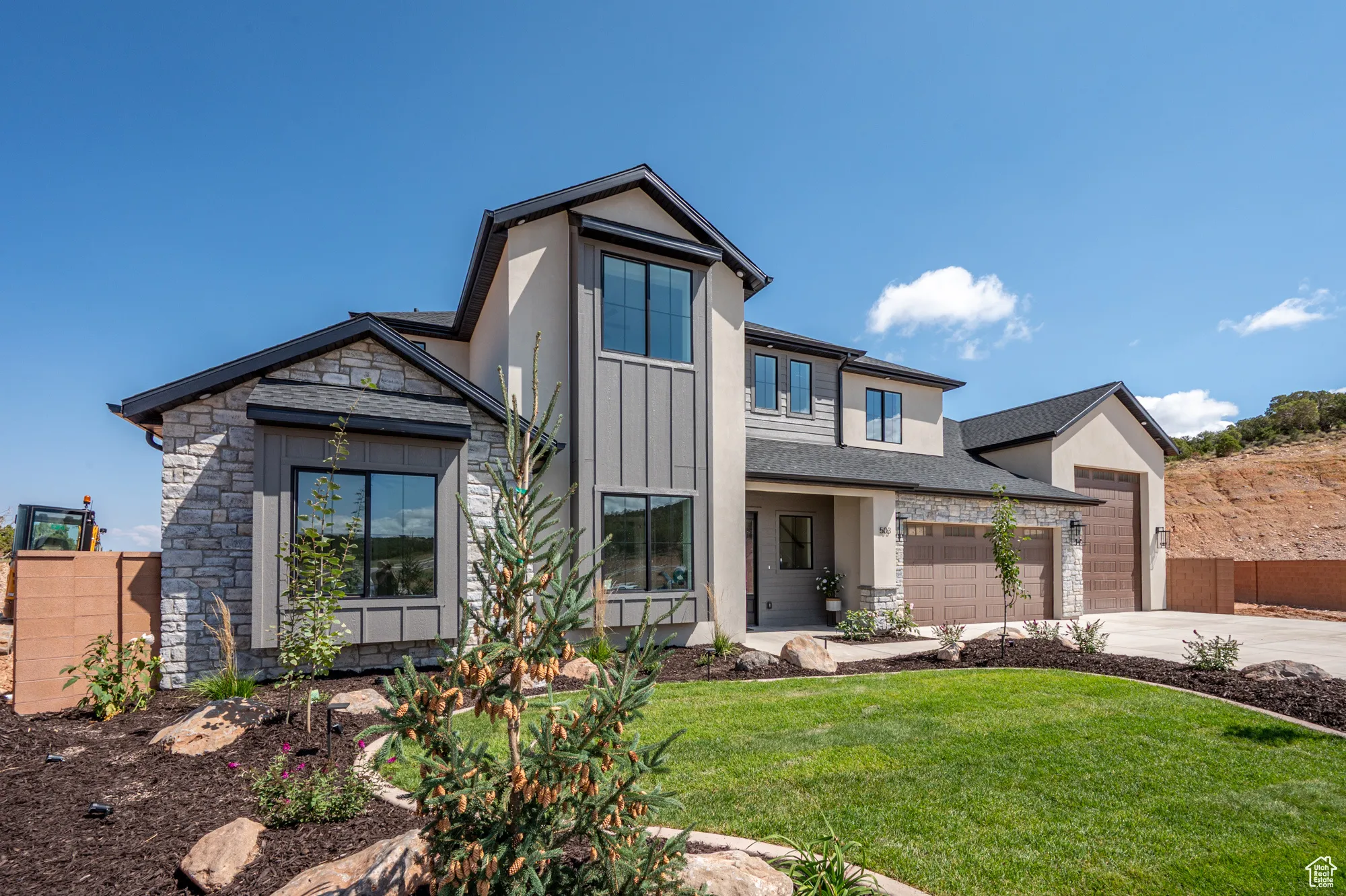 Modern farmhouse style home featuring stone siding, concrete driveway, board and batten siding, and covered porch