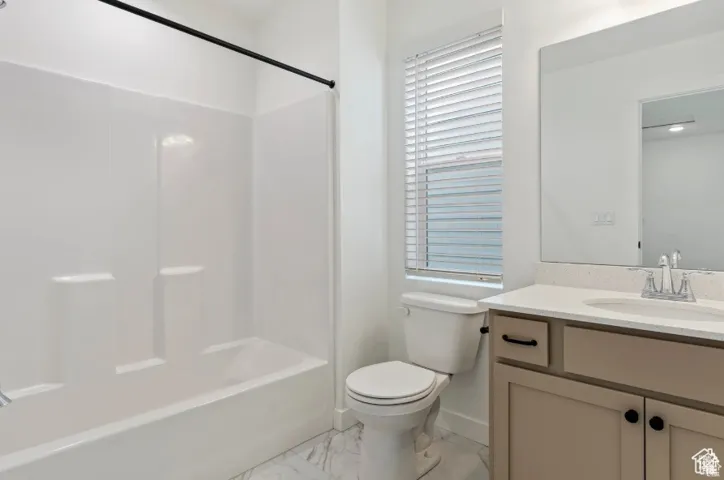 Full bath with marble finish floor, toilet, vanity, and shower / washtub combination