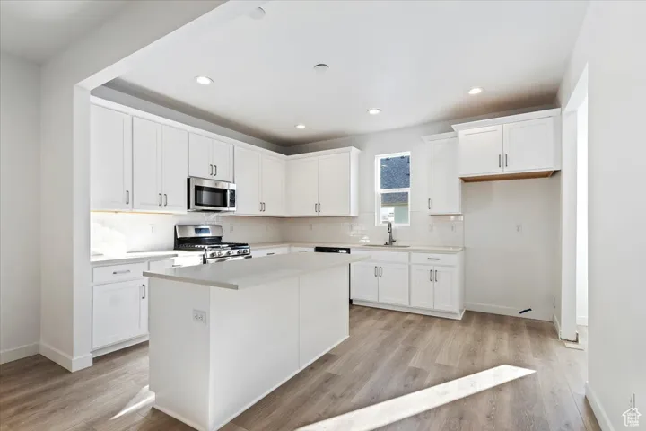 Kitchen featuring a sink, tasteful backsplash, appliances with stainless steel finishes, and light wood-type flooring