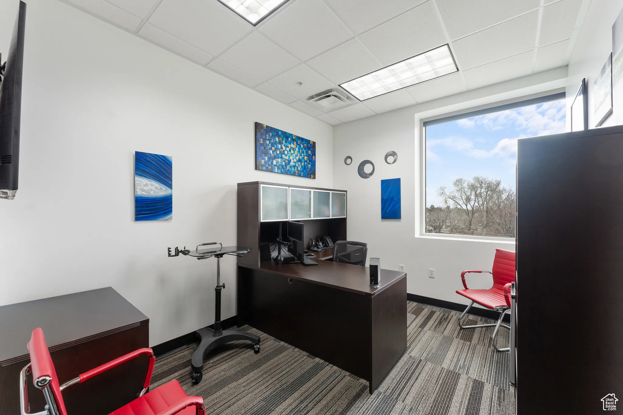 Office space featuring baseboards, carpet flooring, visible vents, and a drop ceiling