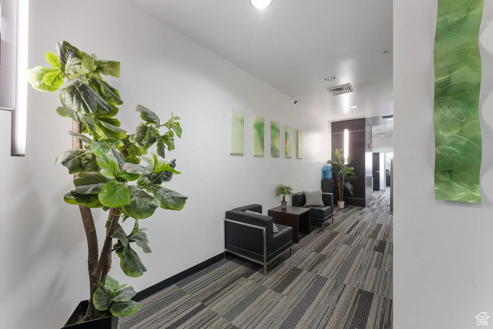 Hallway with dark carpet, baseboards, and visible vents