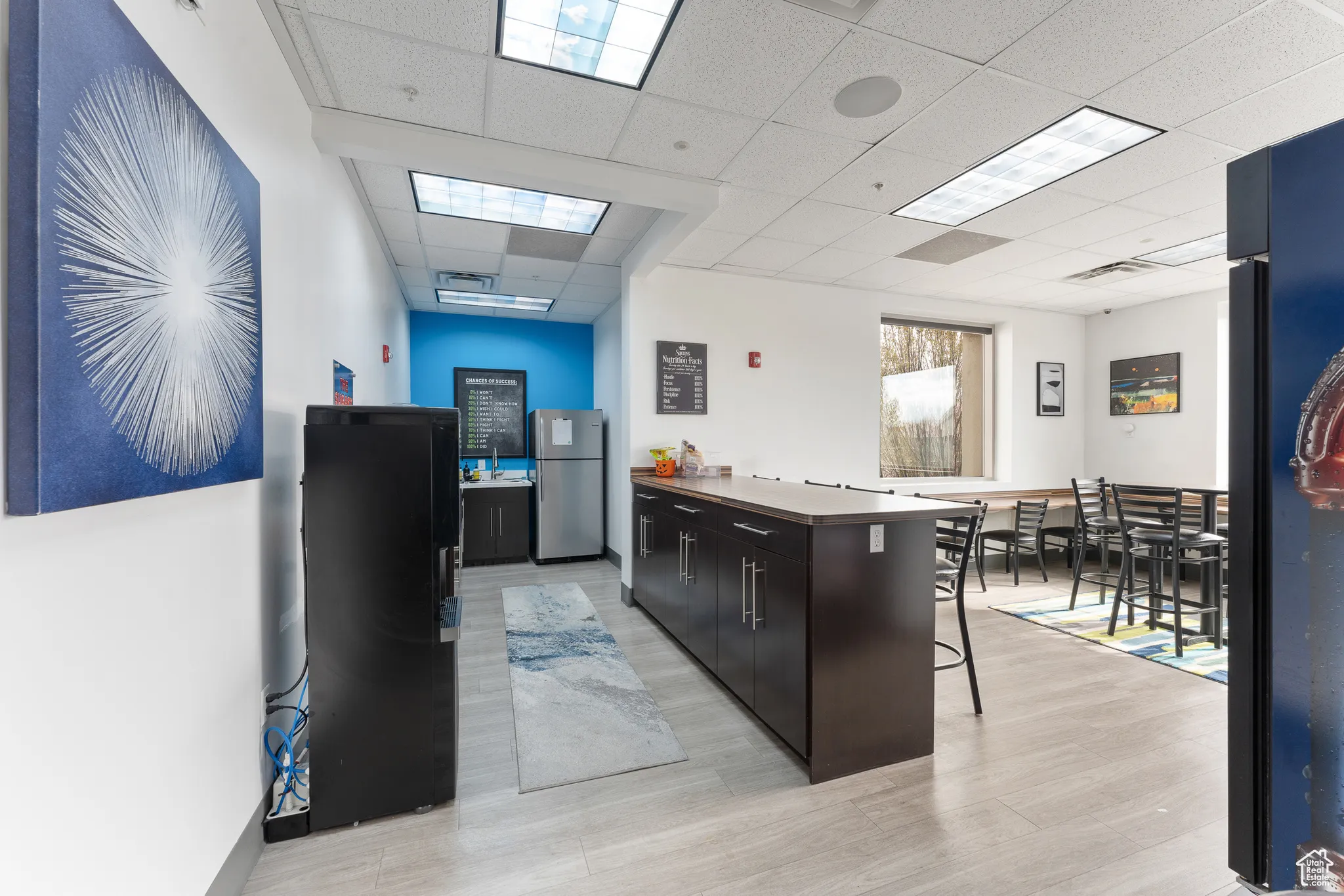 Kitchen featuring a breakfast bar, visible vents, a drop ceiling, and freestanding refrigerator