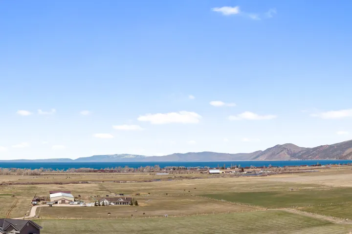 Expansive landscape featuring a large body of water, distant mountains, and open fields