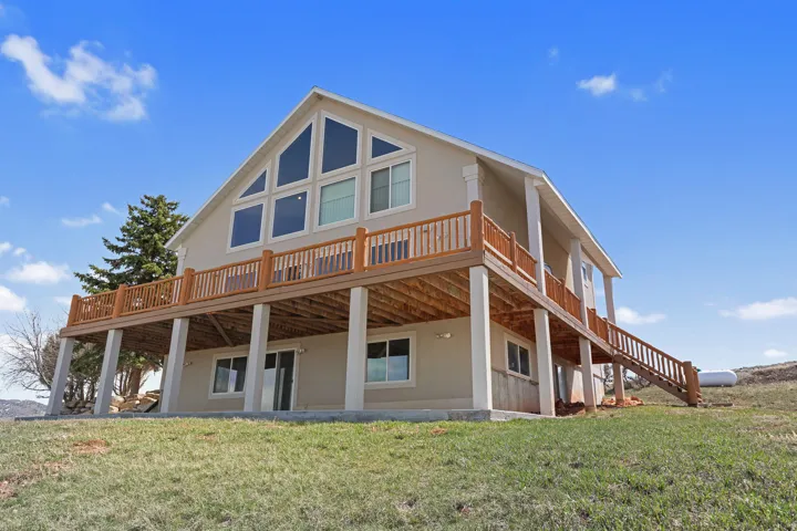Contemporary-style residence featuring a prominent full-width upper-level deck with wood railing